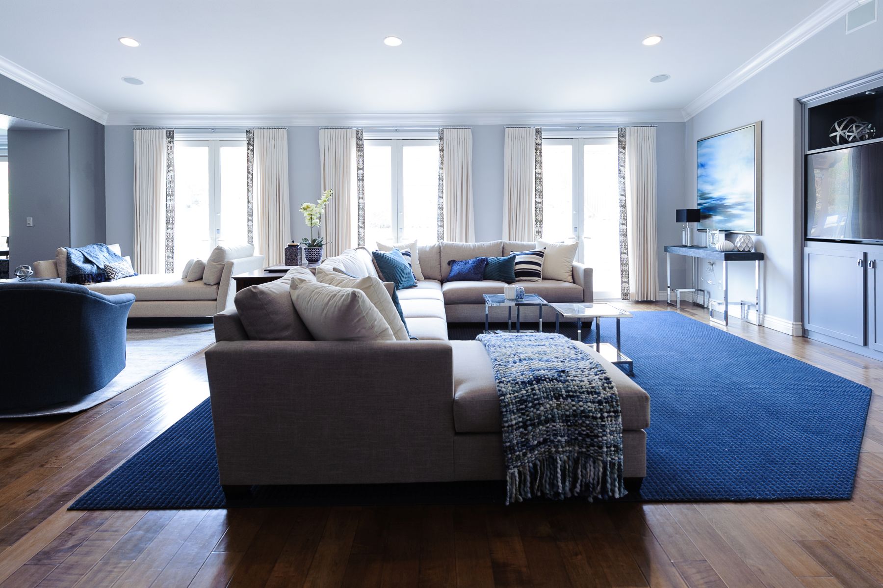 Living room with layered textiles, textured rug, upholstered furniture, and wood flooring