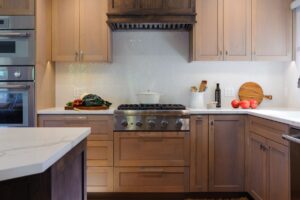 Warm wood kitchen with white herringbone backsplash tile and light countertops