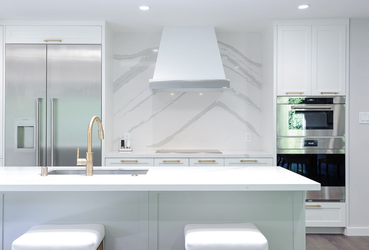 White kitchen with dramatic veined backsplash and matching light countertops.